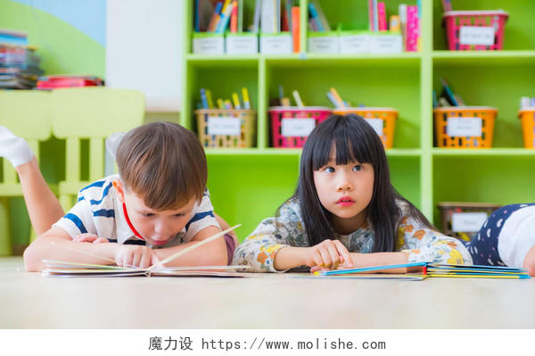 两个孩子躺在地板和阅读故事书在学龄前库中